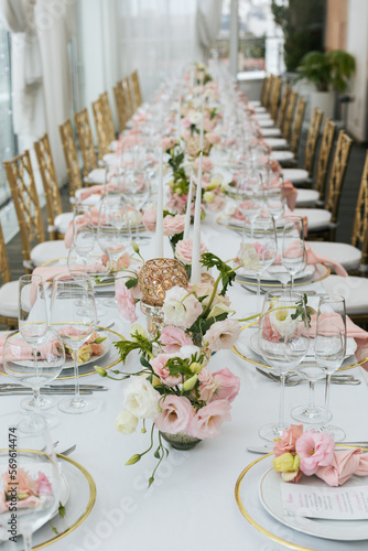 Wedding decorations. Served wedding table with decorative fresh pink flowers and candles. Celebration details. Flower composition roses plates and candles in candlesticks