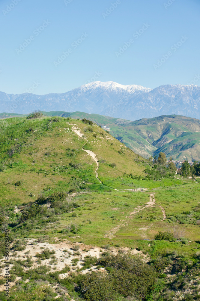 hiking trail across hillside with snowcapped mountain background