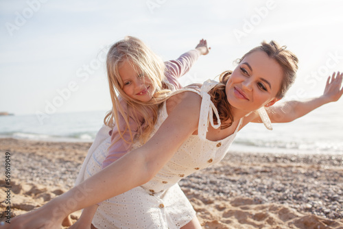 Mither holds the doughter hand and walks in the baech together against the background the sea or coean photo