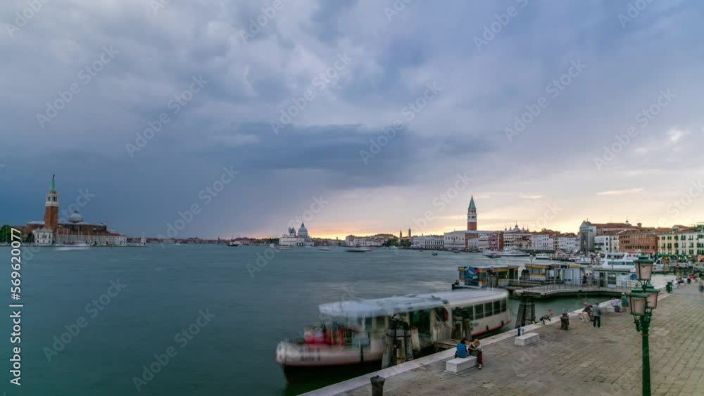 Basilica Santa Maria della Salute, Cathedral of San Giorgio Maggiore during sunset timelapse, Venice, Italy. San Marco campanile on background. Orange cloudy sky. Boats and ship on Grand Canal Basilica Santa Maria della Salute, Cathedral of San Giorgio Maggiore during sunset timelapse, Venice, Italy. San Marco campanile on background. Orange cloudy sky. Boats and ship on Grand Canal