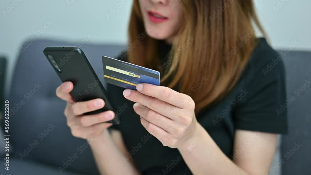 Cropped shot of Asian woman while using credit card for shopping online on mobile phone applications. Cropped shot of Asian woman while using credit card for shopping online on mobile phone applications.