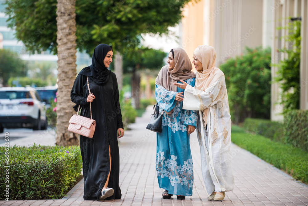 Fototapeta premium Three women friends going out in Dubai. Girls wearing the united arab emirates traditional abaya