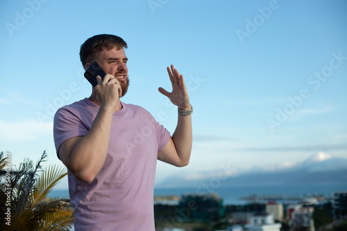 Young negative angry frustrated stressed man is talking on cell mobile phone, calling on smartphone, arguing