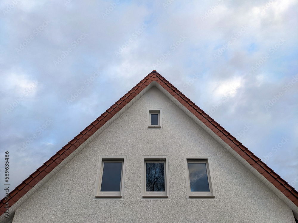 Konzept Wohnungsmarkt oder Hausbau: Frontalansicht auf den Giebel eines neuen oder frisch sanierten Hauses mit heller Fassade und Fenstern mit Himmel und viel Copy Space