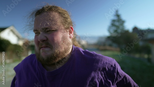 One desperate young fat man feeling upset. Overweight person feeling angry suffering from emotional problems walking outdoors. Tracking shot