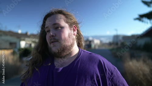 Funny Young happy man takes off the rubber band from his hair outside. An overweight person feeling free shaking head with long hair