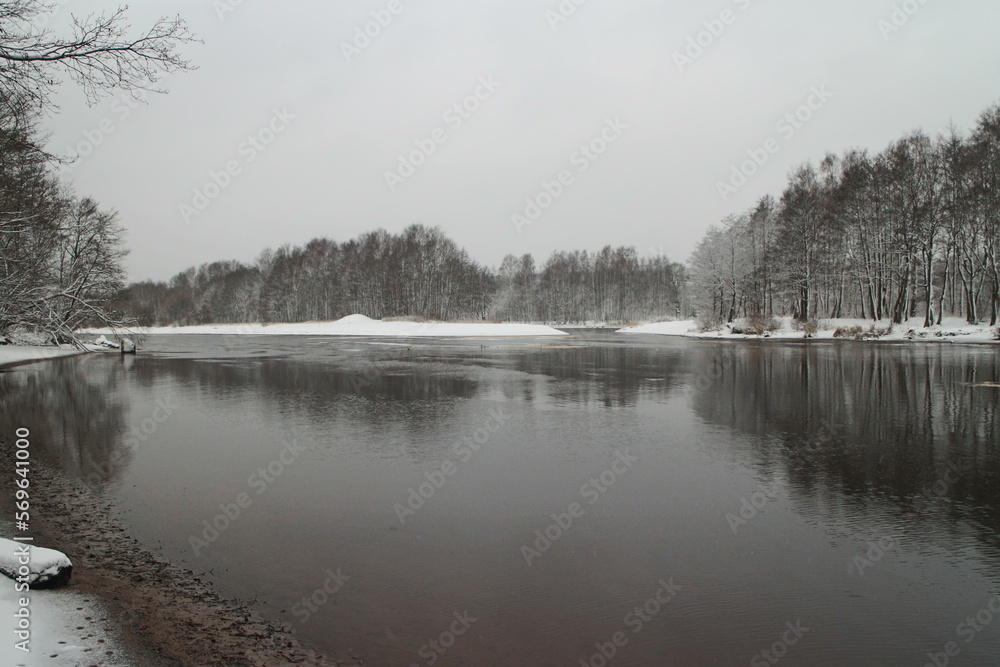 river winter landscape, the banks of the river are covered with white snow, the water is covered with the first ice river winter landscape, the banks of the river are covered with white snow, the water is covered with the first ice