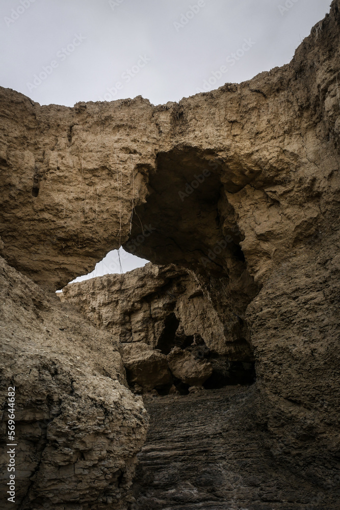 Natural arch made out of clay dirt in washed out dry river bed dirt formation in desert