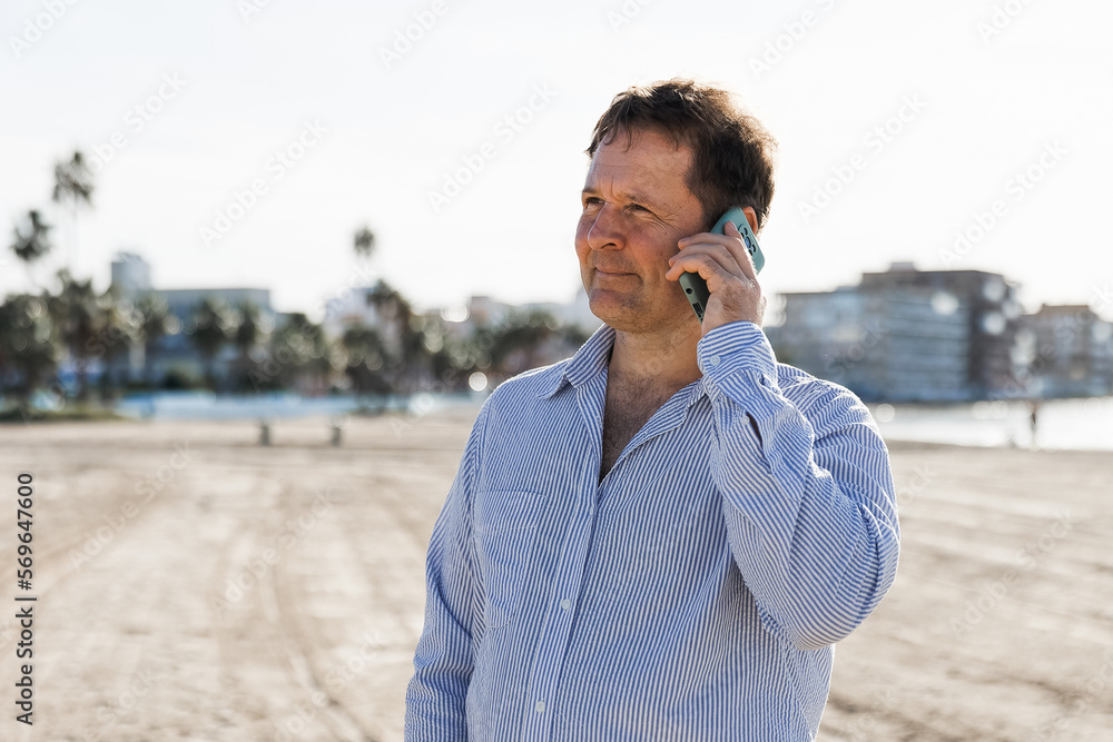 Businessman Talking On Phone, using smartphone mobile apps texting message, surfing social media tech standing in urban city on modern street outdoors. Businessman Talking On Phone, using smartphone mobile apps texting message, surfing social media tech standing in urban city on modern street outdoors.
