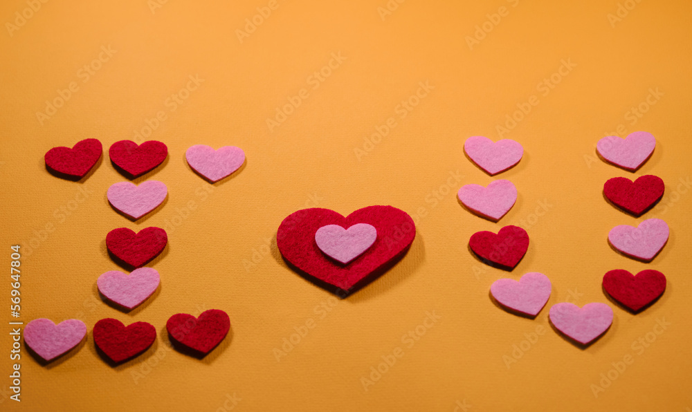 The inscription I love you is laid out on a yellow background of small pink and red hearts. View from above. The concept of Valentine's Day. The inscription I love you is laid out on a yellow background of small pink and red hearts. View from above. The concept of Valentine's Day.