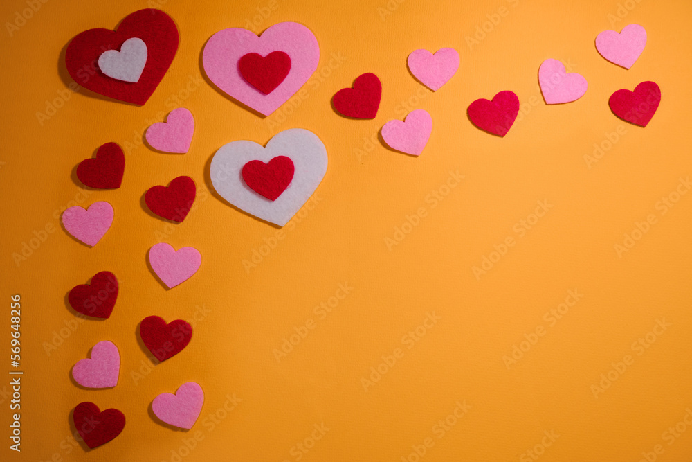 The copy space frame is lined with small pink and red hearts on a yellow background. View from above. Flatlay greeting card. The concept of Valentine's Day.