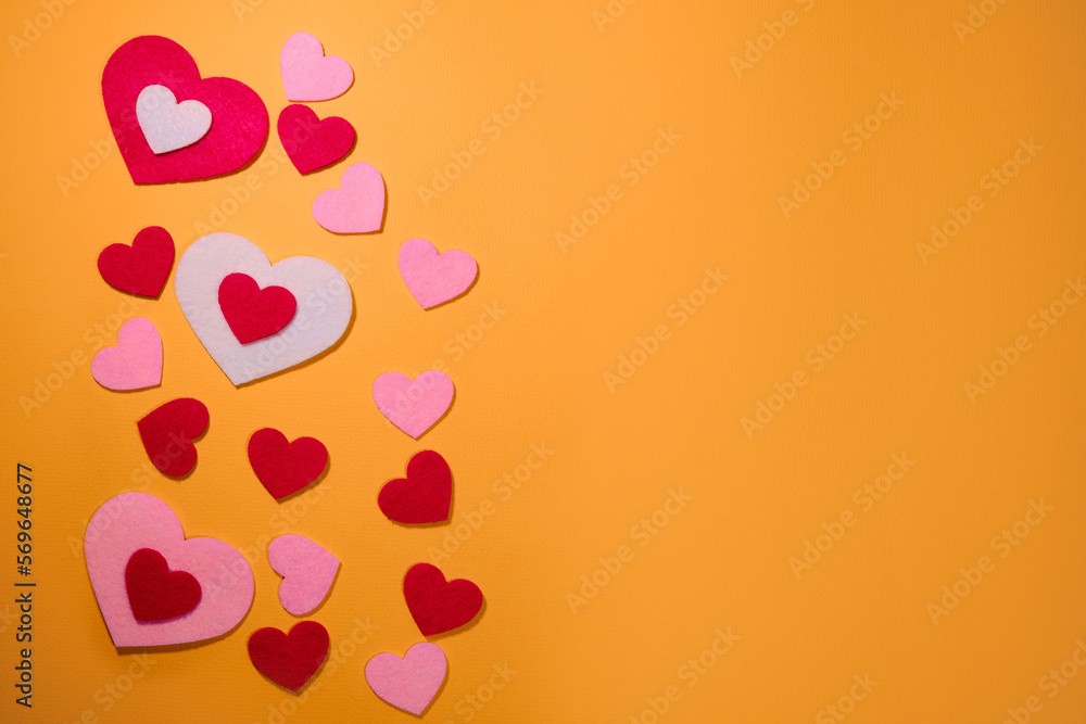 Small pink and red hearts on a yellow background. Top view. Flatlay with copy space greeting card. The concept of Valentine's Day.