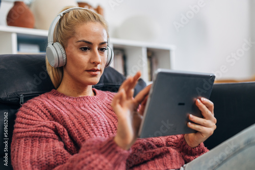 Blonde woman is using a tablet with headphones on