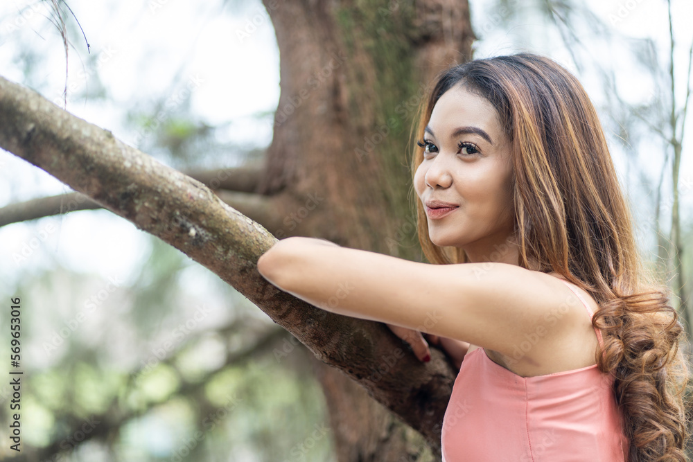 Young woman in pink dress enjoying the tranquil scenery with bokeh park background
