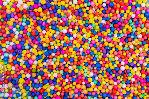 Bright background of scattered multicolored round candies, dragees. Sugar candies. A fun holiday. Children's sweets.