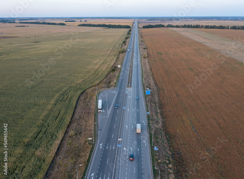 photo from the drone of the autobahn, which goes between the fields. There are markings and cars on the road. The road goes into the distance into the horizon