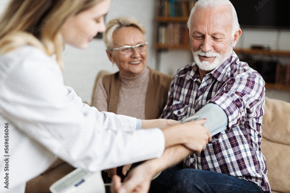 Female nurse checking blood pressure of a senior man during her home visit Female nurse checking blood pressure of a senior man during her home visit