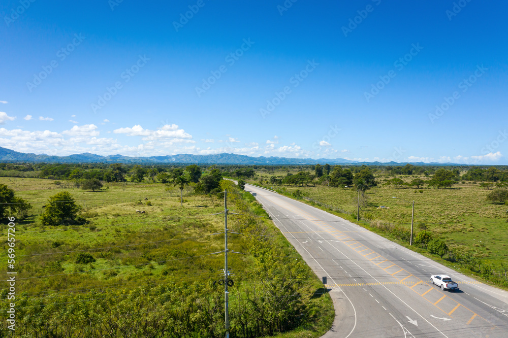 Asphalt highway through green tropical field. Aerial view