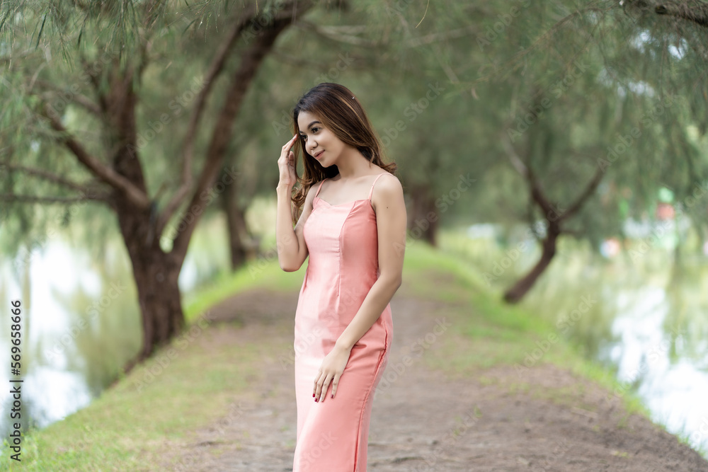Stylish woman embraces comfort in pink dress against bokeh park background Stylish woman embraces comfort in pink dress against bokeh park background