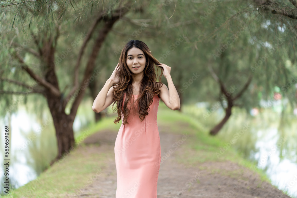 Stylish woman embraces comfort in pink dress against bokeh park background