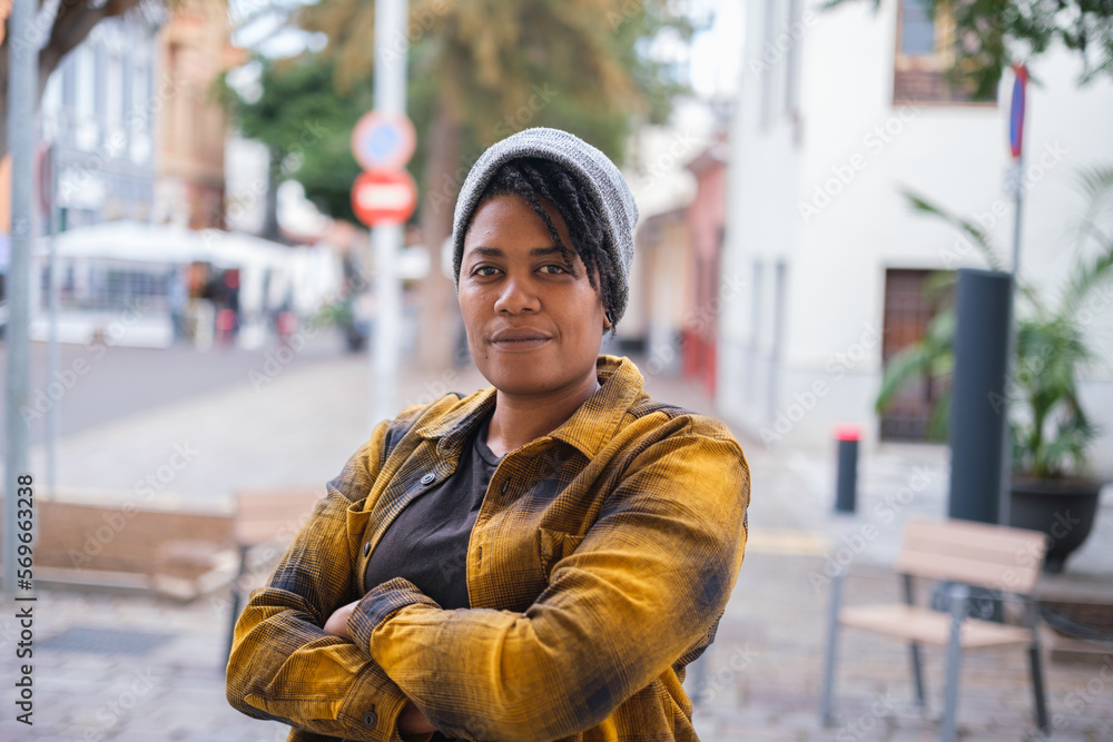 Fototapeta premium Portrait of young woman with dreadlocks and urban style type hat outdoors in the city streets. Concept: hairstyle, urban style, lifestyle