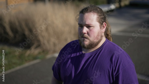 One worried overweight man standing outside with preoccupied expression. A thoughtful fat guy close up face with anxious emotion. Tracking shot