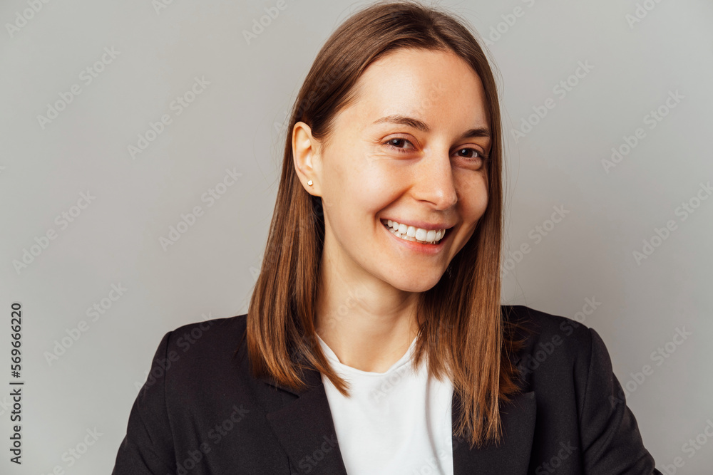 Simple studio portrait of s wide smiling natural young woman over grey background. Simple studio portrait of s wide smiling natural young woman over grey background.