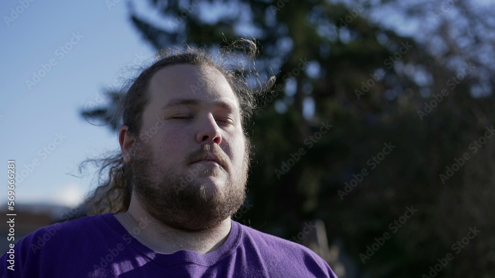 One meditative overweight young man in contemplation outside. Close up face of a relaxed person with eyes closed in meditation One meditative overweight young man in contemplation outside. Close up face of a relaxed person with eyes closed in meditation