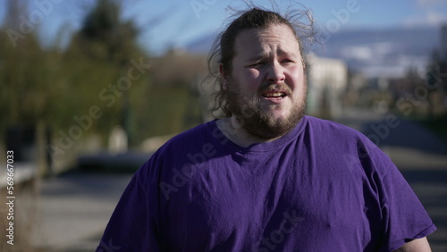 One frustrated overweight young man standing outdoors feeling regret. Anxious upset person hitting himself in the head in anguish due to failure