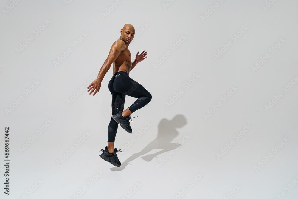 Active sporty man with naked torso jumping on white studio background. Sport and healthy lifestyle