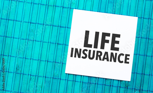 life insurance word on torn paper with blue wooden background