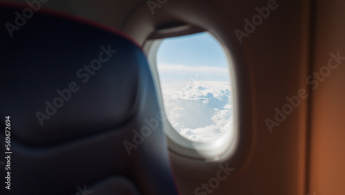 The interior of an airplane with a porthole flies in the sky with white clouds. Travel, business and transport, concept