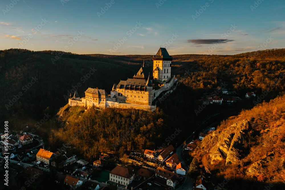 Naklejka premium Aerial view of gothic Royal Karlstejn Castle with Czech crown jewels,Czech Republic.Most popular Czech castle at sunset.Amazing historical monument in central Europe.Czech landmark,tourist attraction