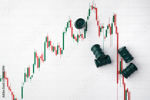 Miniature barrels and graphs of stock fluctuations. Selective focus. The concept of rise and fall in the value of oil products and company shares.