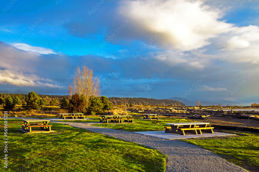 Early spring sunset time, picnic area near the shore , Picnic tables on