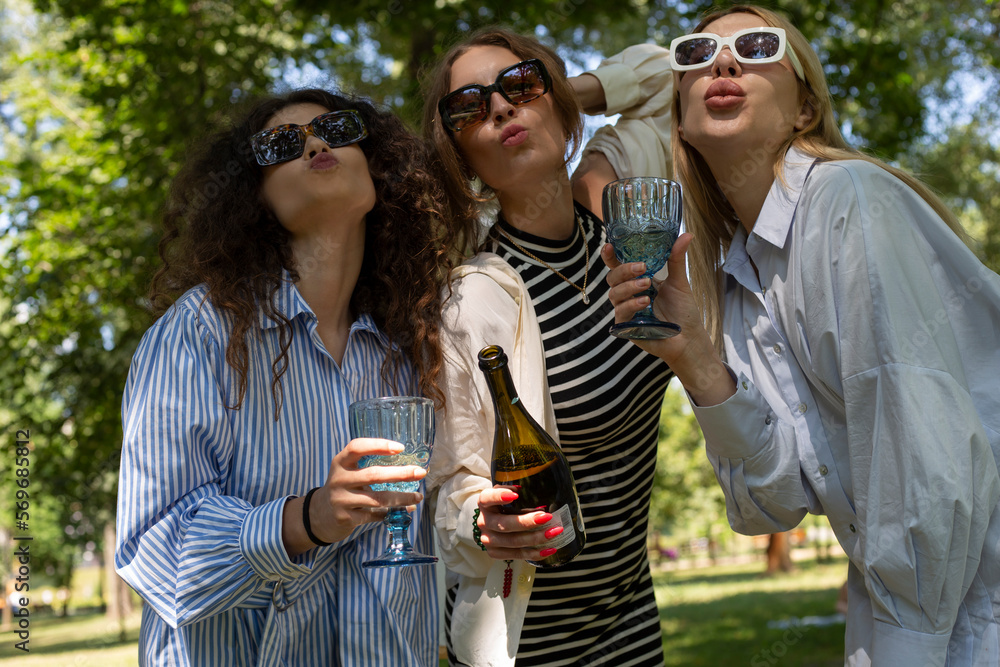 Fototapeta premium Art picnic in spring drinking wine, laughing, taking pictures on polaroid and having a great time with friends having delicious snacks 