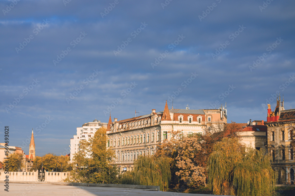 Oradea Art Nouveau with its intricate details and ornate facades. Capture the serene beauty of the Crisul Repede River, with its bridges, parks, and scenic walkways