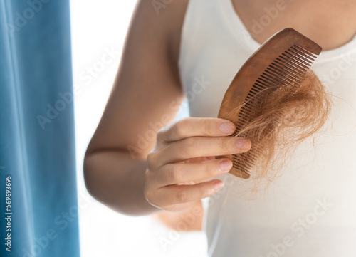 Hair loss problem, postpartum period, menstrual or endocrine disorders, hormonal imbalance, stress concept. Many hairs fall off after brushing. Female detangles hair with a comb photo