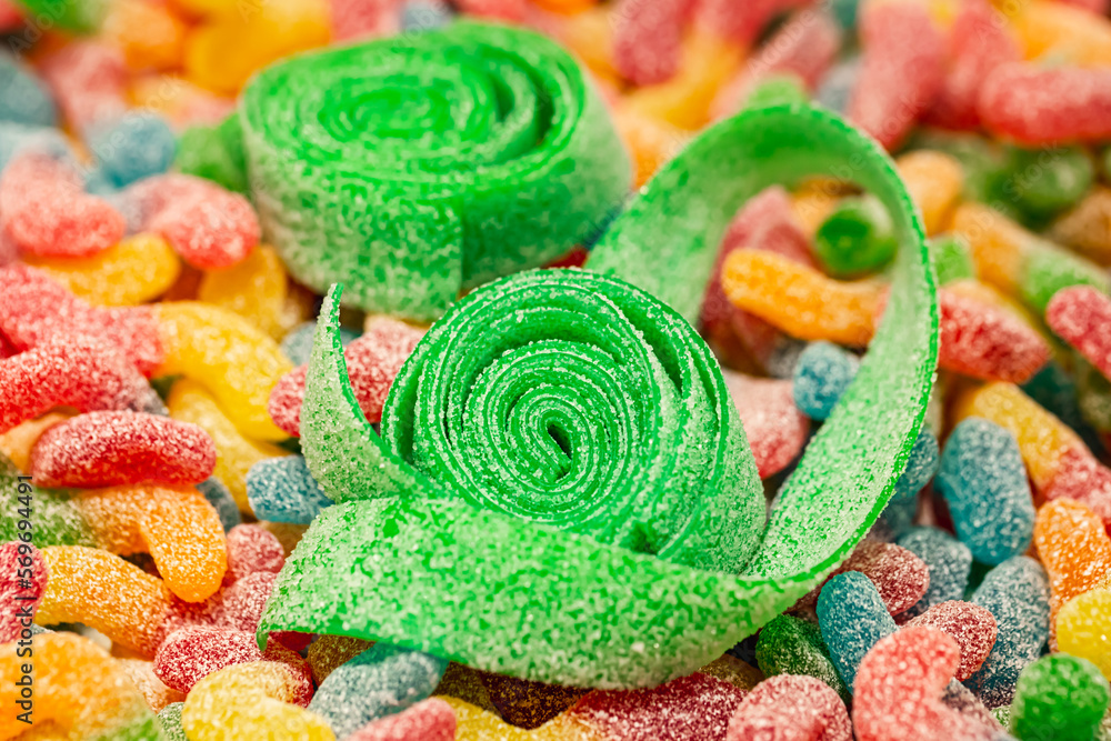 Close-up, background with green rolled gummies coated with sugar, macro shot.