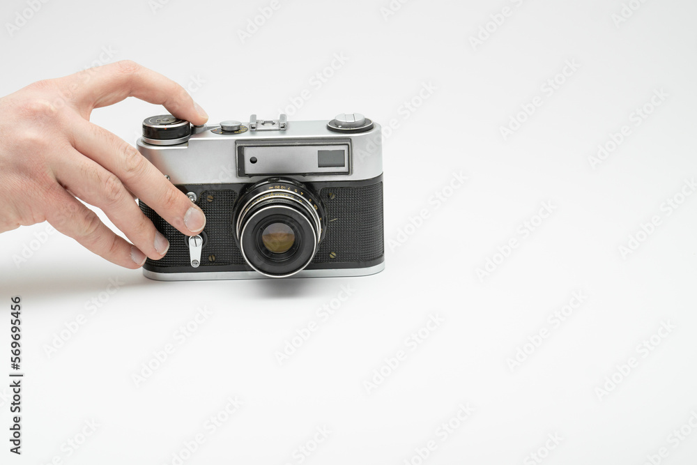 Hand pressing the shoot button on a vintage film camera isolated on white backgorund. Hand taking picture with an old film camera. Finger pressing the shoot button on a film camera 