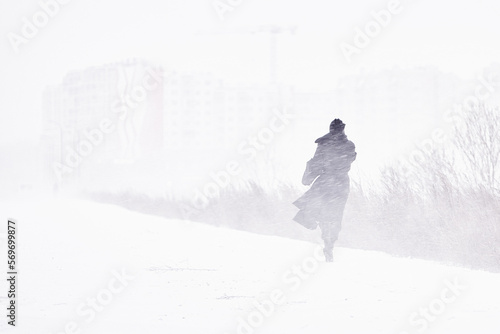 silhouette of a man walking in a snowstorm in the city the concept of a storm blizzard and bad weather.