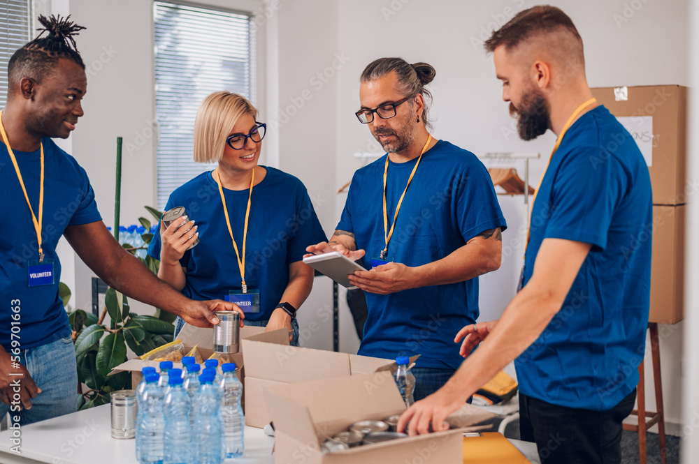 Diverse volunteers working in a charity donation center and packing clothes and food Diverse volunteers working in a charity donation center and packing clothes and food