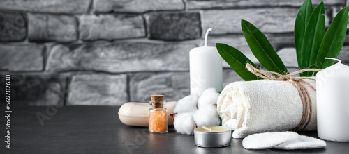 Wellness accessories on gray stone background. Towel, candles and aromatic salt.