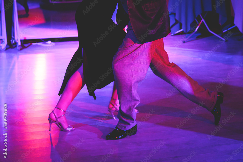 Couples dancing traditional latin argentinian dance milonga in the ballroom on a festival, tango studio, salsa, bachata and kizomba lesson in the red and purple lights, rehearsal in the dance class