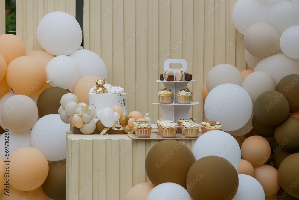 Creative gender neutral baby shower or birthday decoration in the garden. Bohemian style outdoor event set up with balloons. White cream peach caramel balloon arch kit. Creative gender neutral baby shower or birthday decoration in the garden. Bohemian style outdoor event set up with balloons. White cream peach caramel balloon arch kit.
