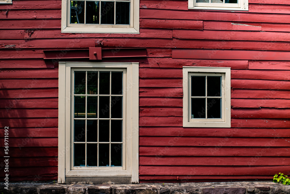 Exterior wood clad red barn wall with white framed windows Exterior wood clad red barn wall with white framed windows