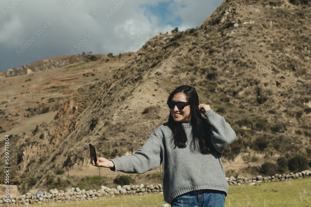 Woman taking a selfie in a mountain landscape in the Andes mountains (South America) enjoying her vacation. Concept professions, people, travels and vacations.