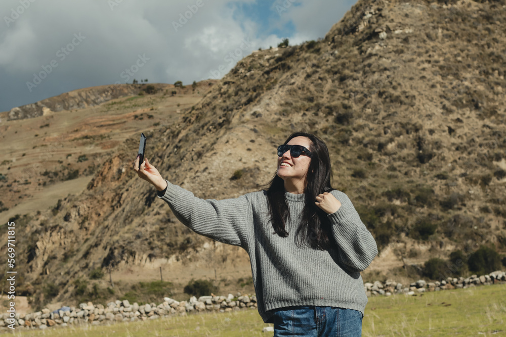 Woman taking a selfie in a mountain landscape in the Andes mountains (South America) enjoying her vacation. Concept professions, people, travels and vacations. Woman taking a selfie in a mountain landscape in the Andes mountains (South America) enjoying her vacation. Concept professions, people, travels and vacations.