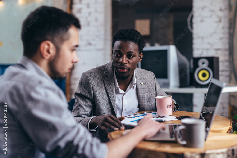 Black executive business owner seated at table with employees. Black executive business owner seated at table with employees.