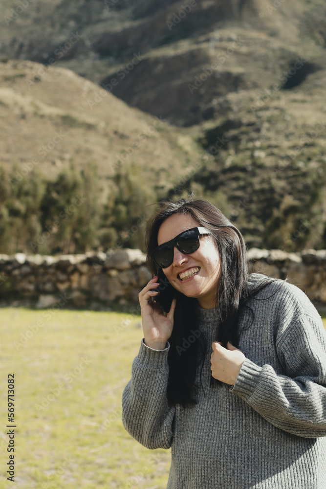 Woman talking on the phone in a mountain landscape in the Andes Mountains (South America) enjoying her vacation. Concept of people, travel and vacation. Woman talking on the phone in a mountain landscape in the Andes Mountains (South America) enjoying her vacation. Concept of people, travel and vacation.